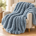 Plaid texturé bleu Cocooning 180 × 200 cm sur un fauteuil — mise en scène illustrative
