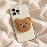 Support de téléphone en peluche ours caramel sur une coque crème — Cocooning